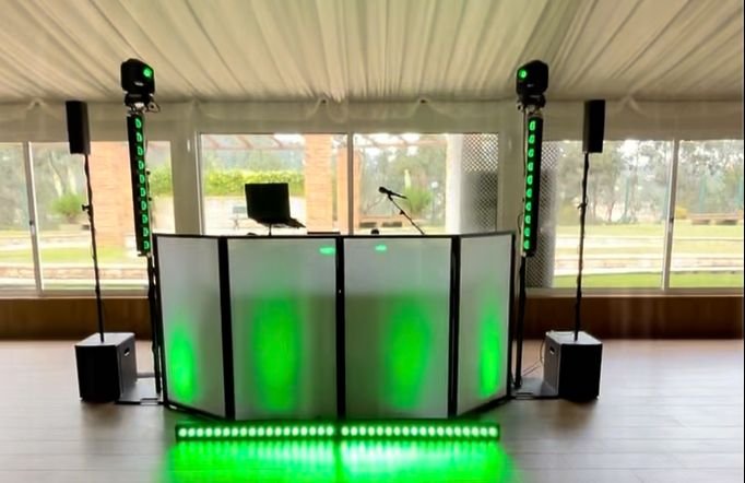 Cabine de DJ Team Brasa com colunas e luzes verdes numa sala com janelas para o jardim