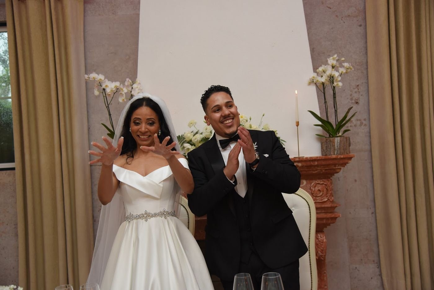 Noivos a celebrar de mãos no ar à mesa principal, num casamento real animado pela Team Brasa