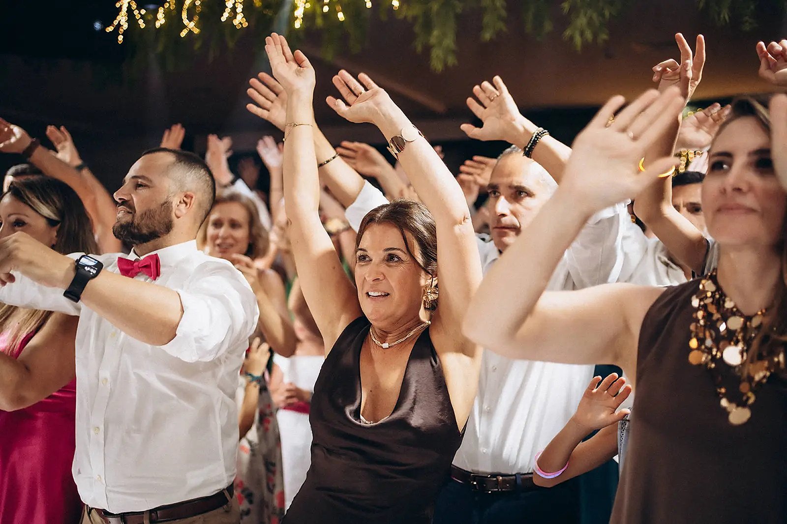 Grupo de mãos no ar na pista, noite de festa