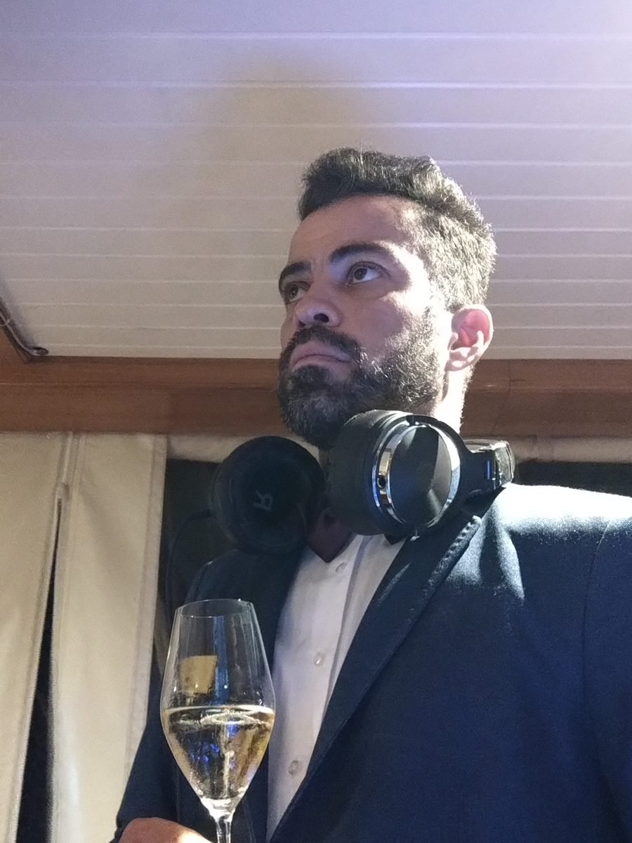 Guga Brasa, founder of Team Brasa, with headphones round his neck and a glass of champagne