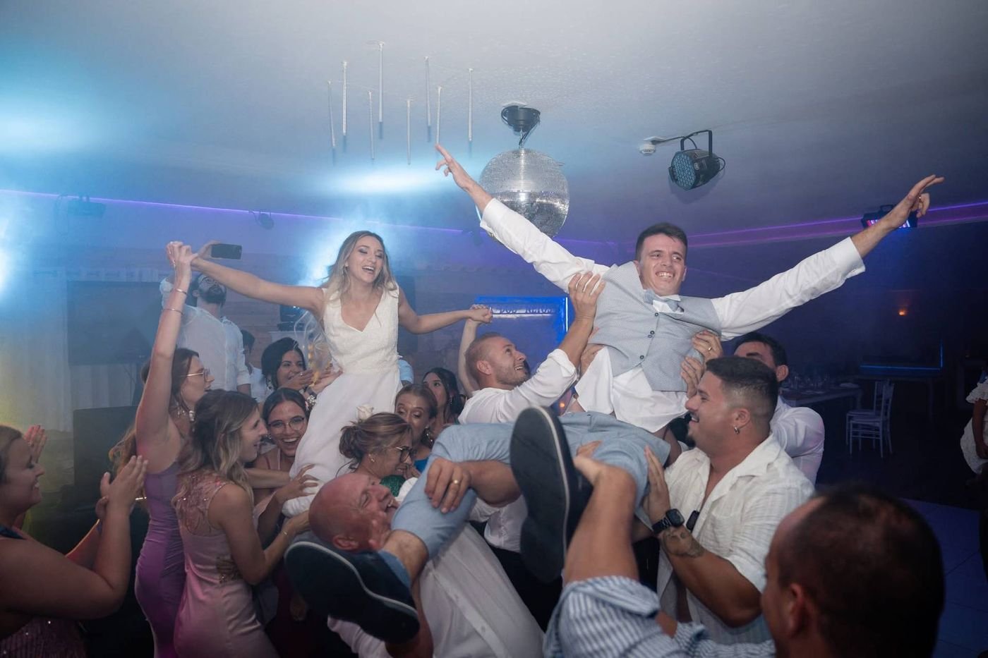 Noivos levantados ao colo pelos convidados, a festa no auge